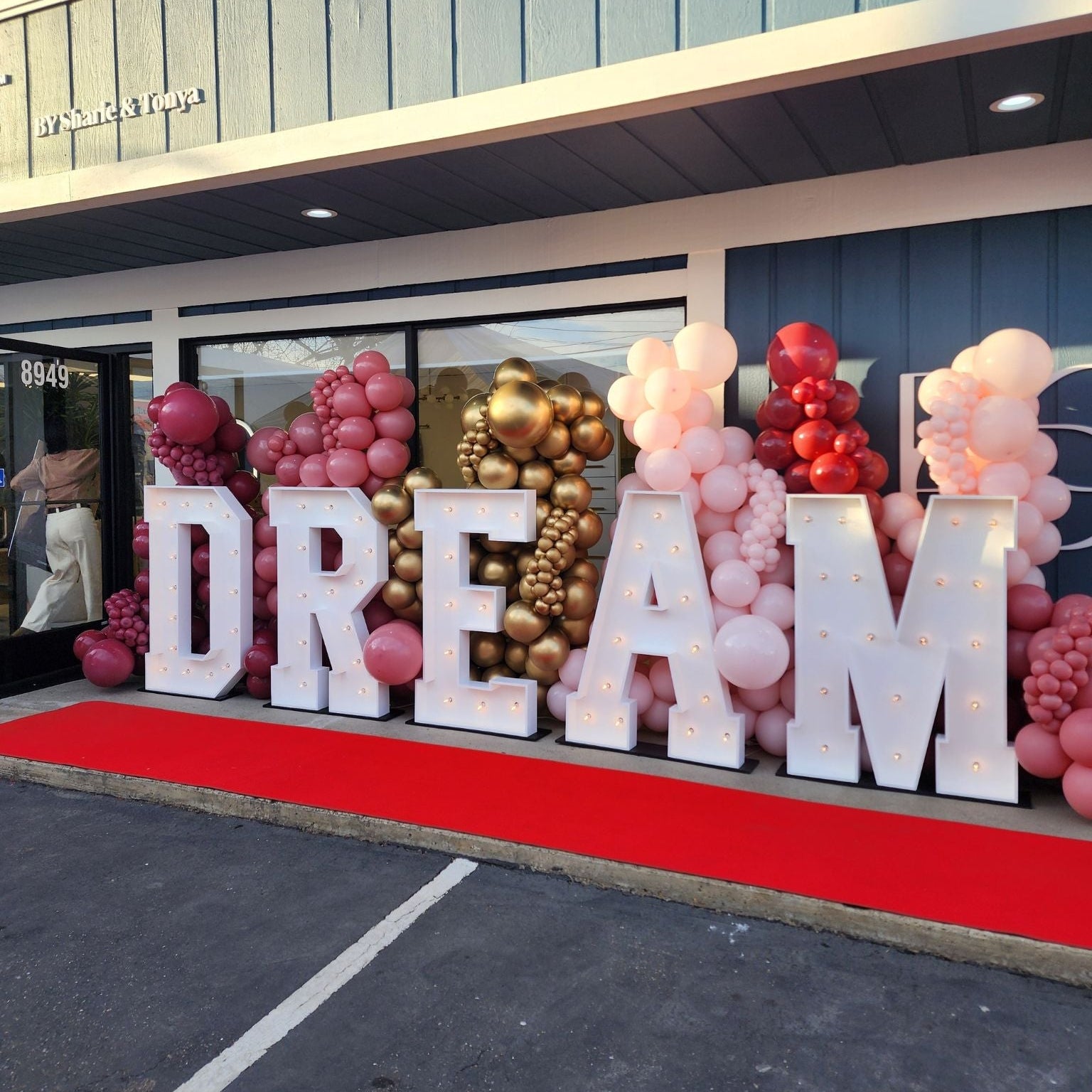 Decorative setup with 'DREAM' letters and balloons in front of a building.