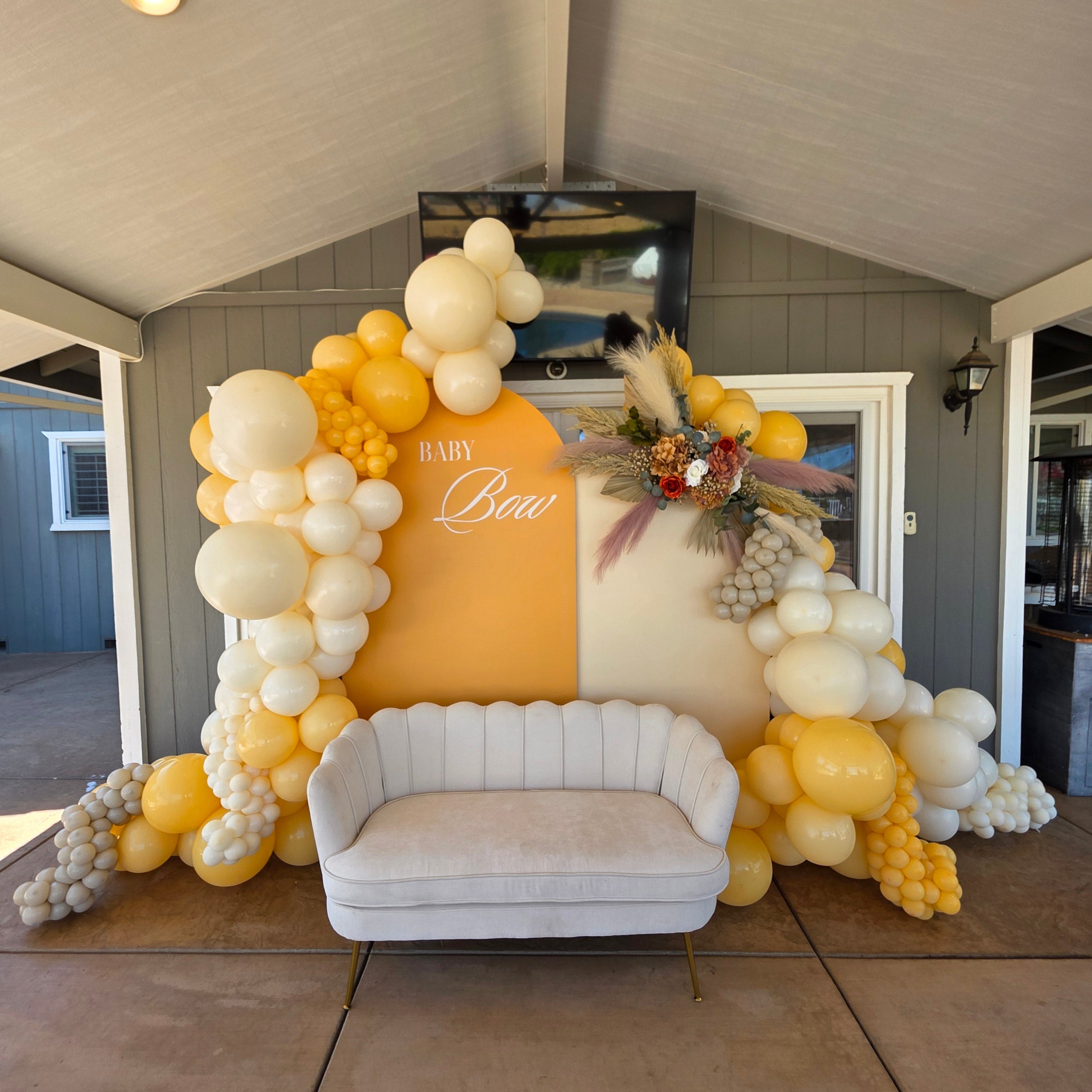 Decorative balloon arch with a couch and decorative items in a room.