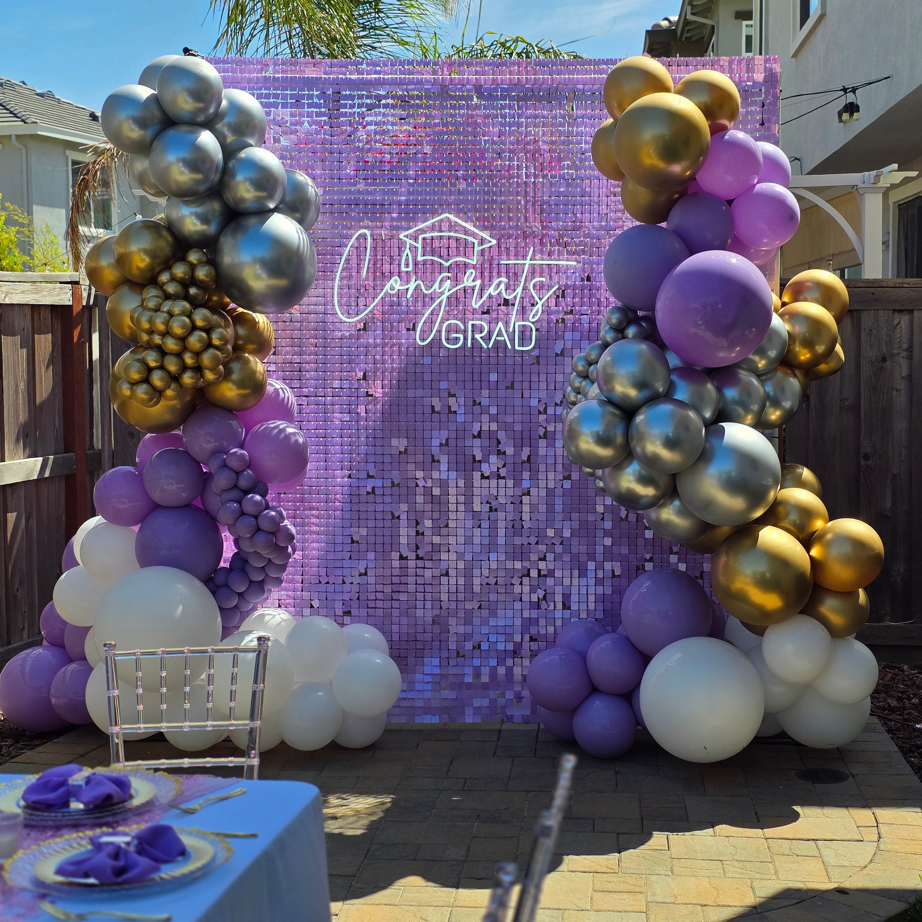 Decorative arch with balloons and 'Congratulations Grad' sign on a purple backdrop